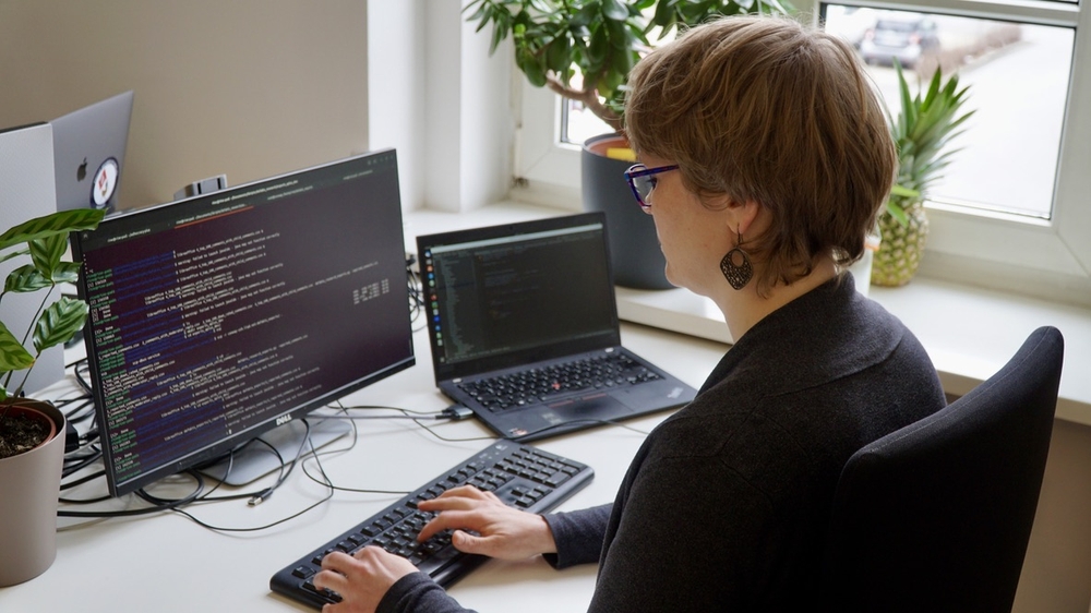Das Bild zeigt Katharina an ihrem Computer. Auf dem Bildschirm ist Code zu sehen.