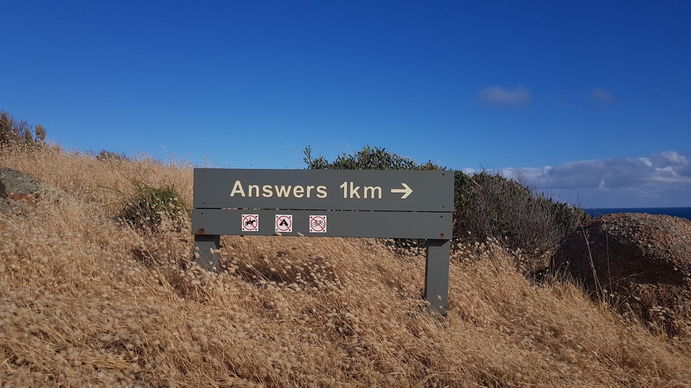Ein Schild auf einer Düne auf dem steht: Answers in 1km