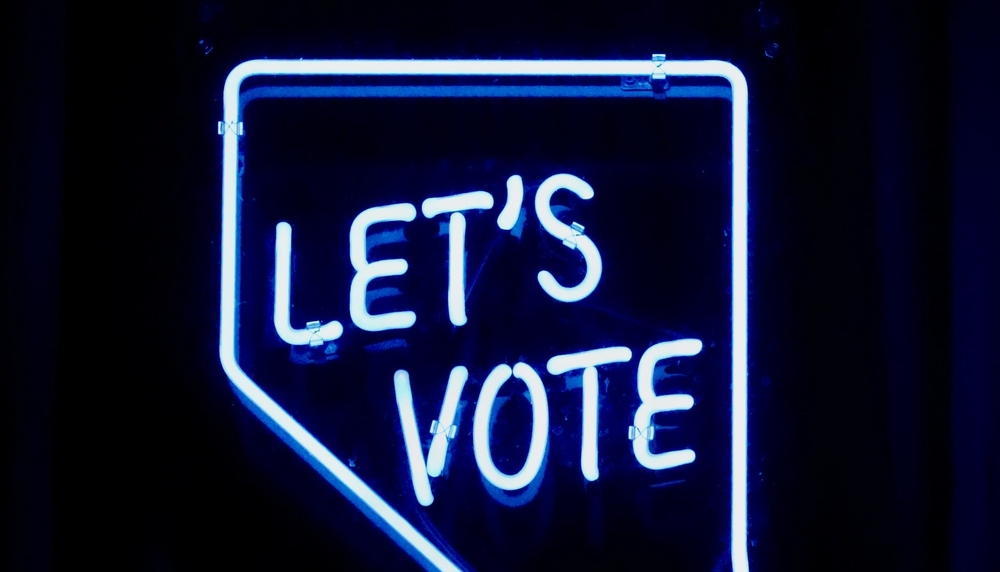 Neon-Leuchtschild mit dem Schriftzug „Let's Vote“